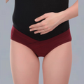 Person wearing maroon  MATERNITY underwear and a black top on a gray background
