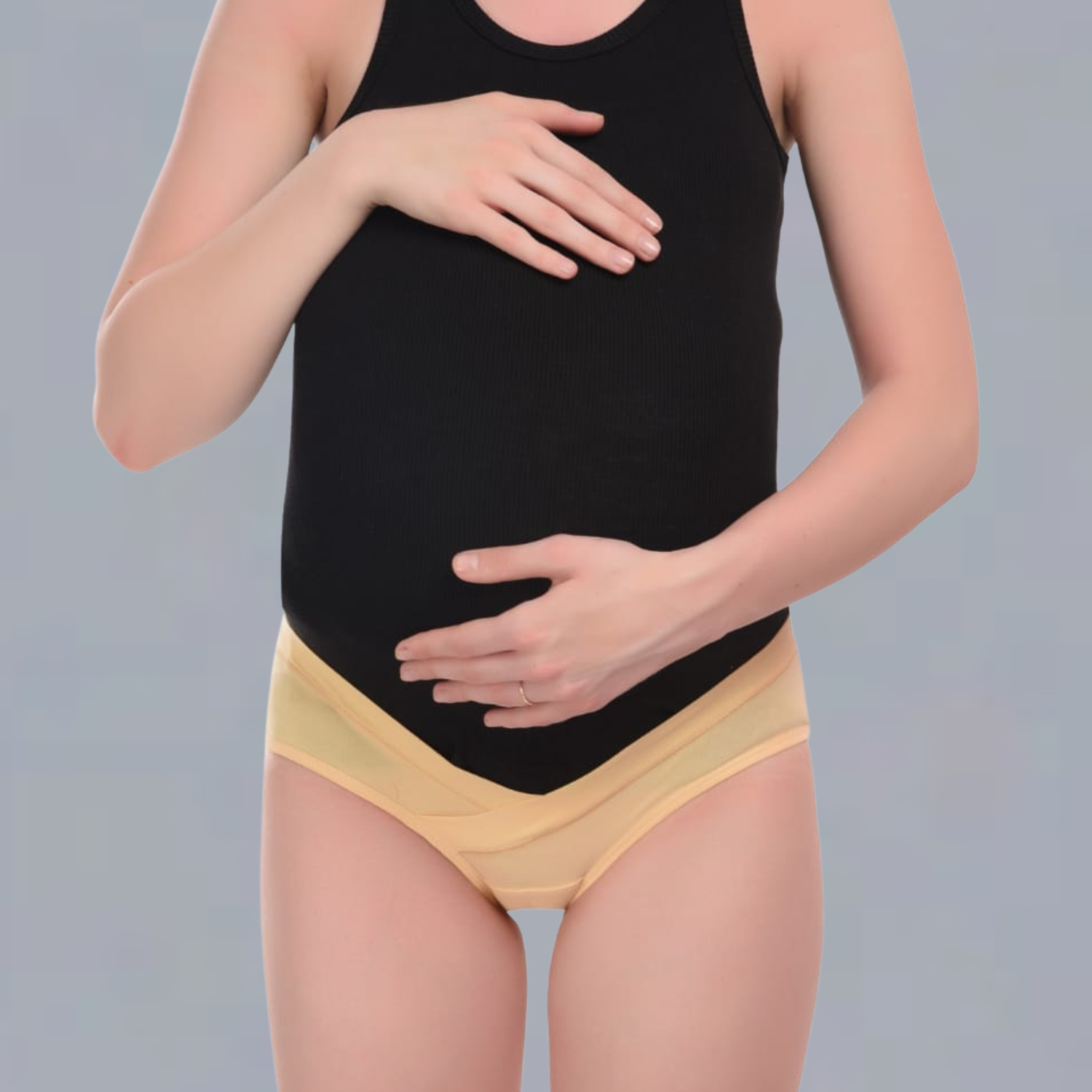 Person wearing a black tank top and yellow  maternity underwear on a gray background